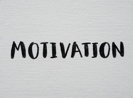 Inspirational word 'Motivation' in black on a white textured canvas background.